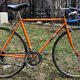 A photo of a bright orange Hi-C branded road bike.